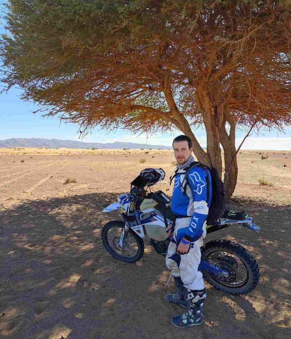 motard à l'ombre sous un arbre dans le désert au maroc
